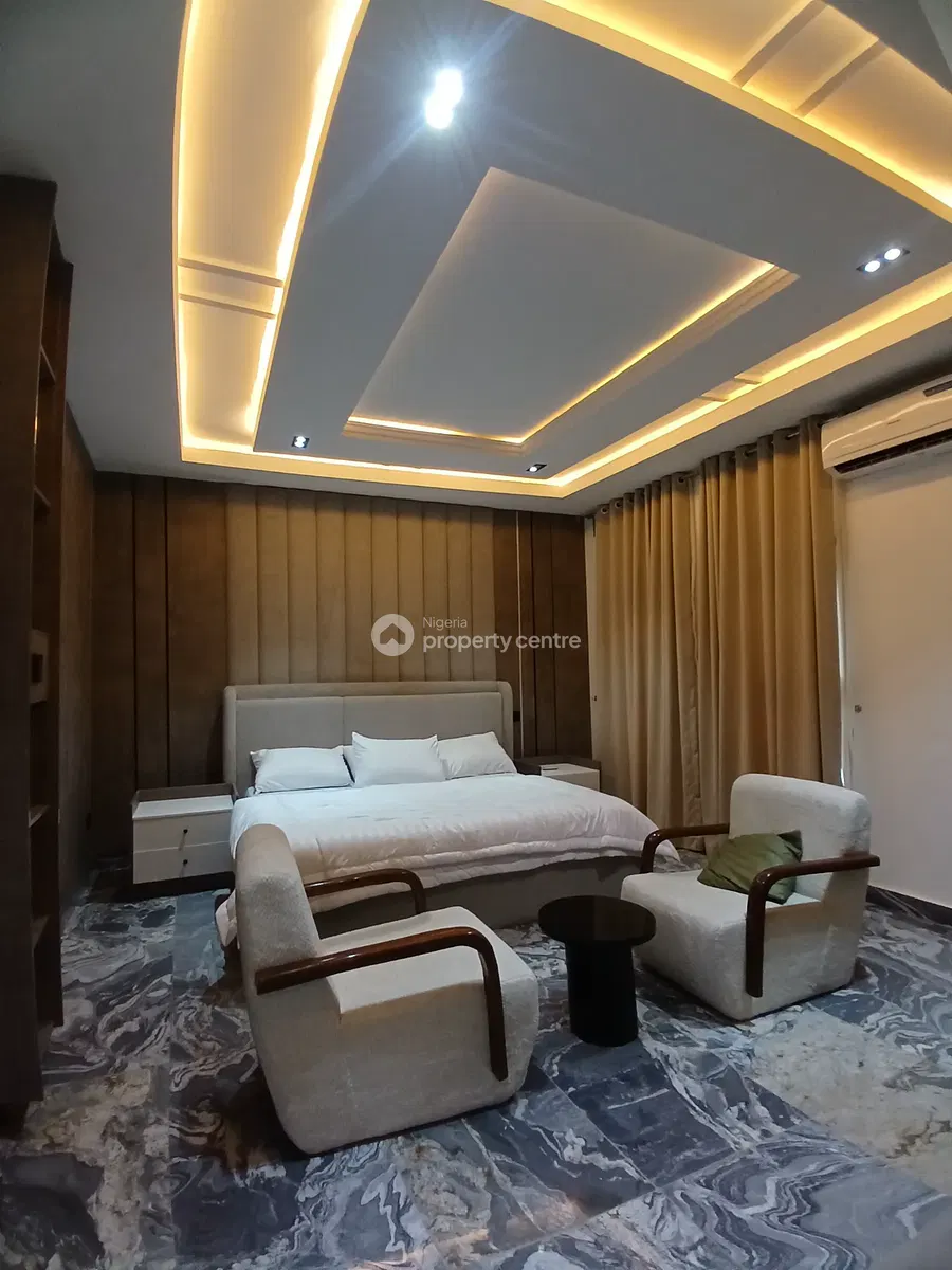 Bedroom with two armchairs and warm ceiling lighting